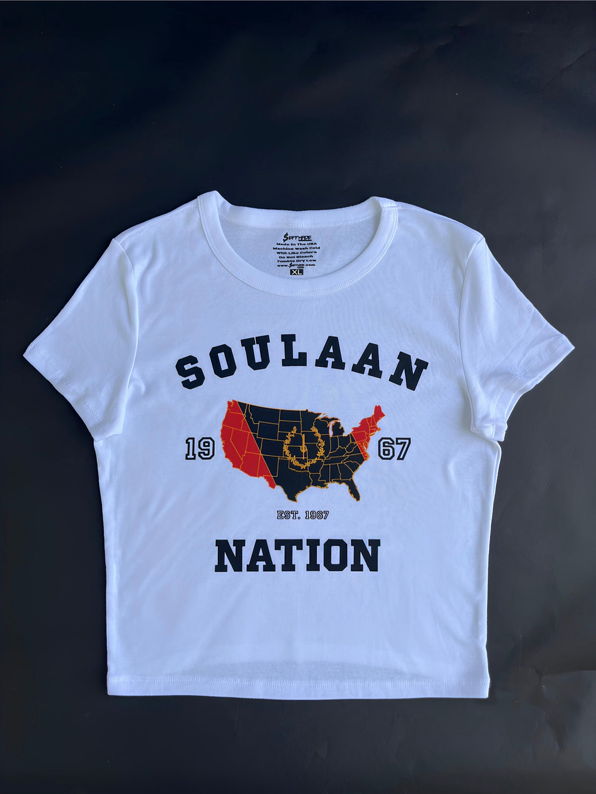 White Soulaan Signature Women’s Baby Tee featuring the words “Soulaan Nation” and “1967,” with a red-and-black United States map, gold outline, gold sword, and gold wreath.