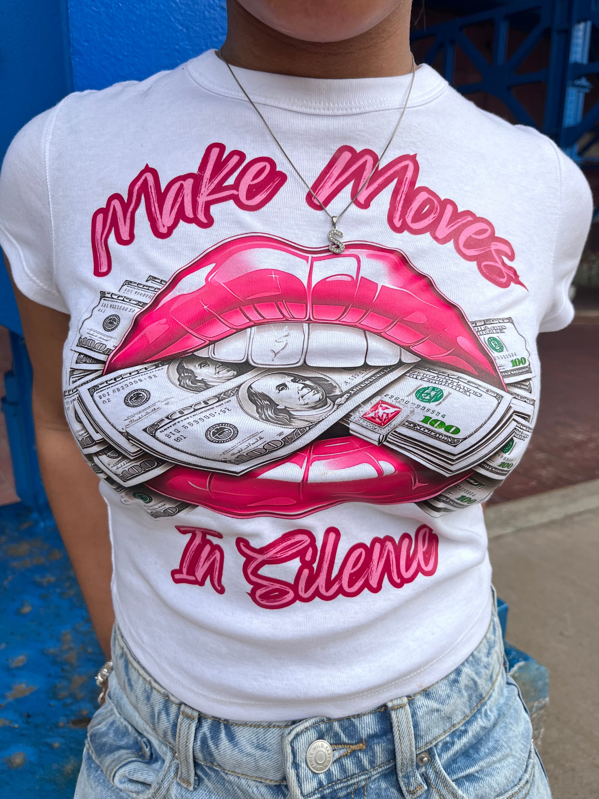 White Make Moves in Silence women’s baby tee featuring a bold hot pink lips-and-money graphic with the words “Make Moves in Silence.” Women’s crop top, graphic T-shirt by Seffmade.