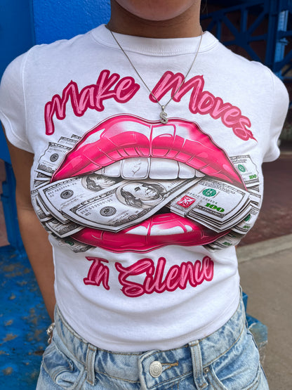 White Make Moves in Silence women’s baby tee featuring a bold hot pink lips-and-money graphic with the words “Make Moves in Silence.” Women’s crop top, graphic T-shirt by Seffmade.