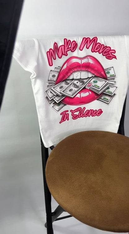 White Make Moves in Silence women’s baby tee featuring a bold lips-and-money graphic with the words “Make Moves in Silence.Women’s crop top, graphic T-shirt by Seffmade on a chair.